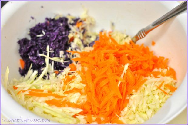 Grated purple and green cabbage, plus carrots in bowl.