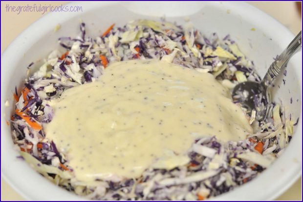 A poppyseed dressing is added to the purple coleslaw, and mixed in.