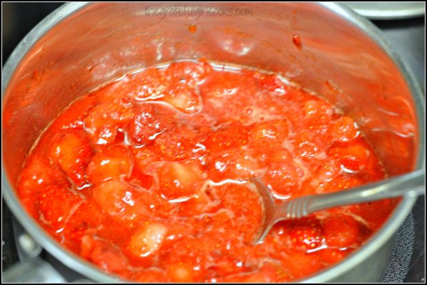 Cooking mashed strawberries in saucepan for strawberry cobbler filling.