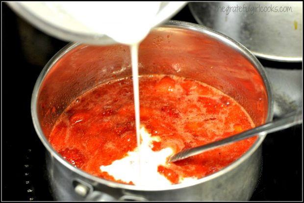 Pouring cornstarch slurry into pan with strawberry cobbler filling.