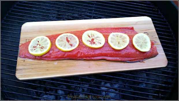 Cedar plank with salmon and lemon slices on grill