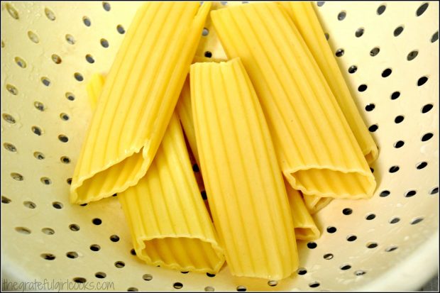 After cooking, the manicotti pasta shells are drained in a colander.