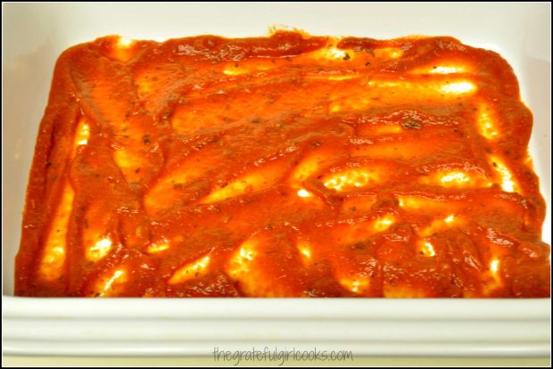 Marinara sauce is spread on the bottom of casserole dish before adding stuffed manicotti.