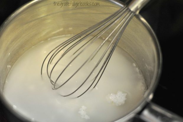 Sugar, cornstarch and water in saucepan with a whisk, making glaze for strawberry pie