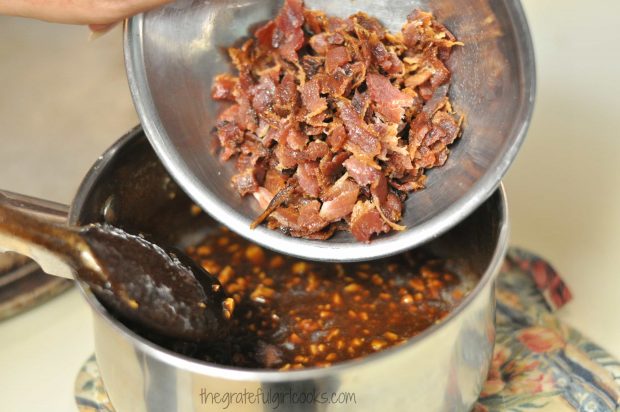 Crumbled, cooked bacon pieces are added to praline mixture in pan.