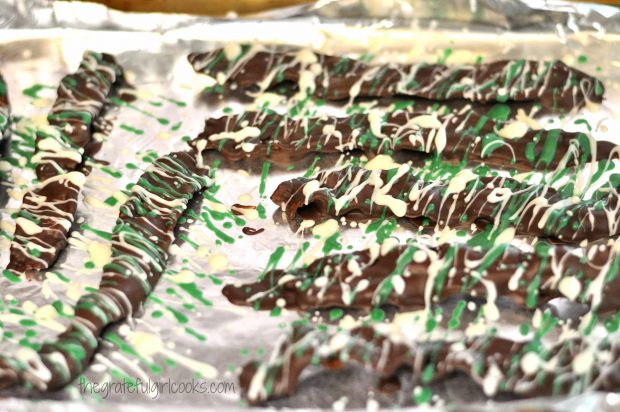 Chocolate covered bacon is drizzled with white and green chocolate