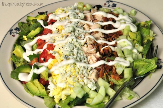 Salad dressing is drizzled over cobb salad, ready to serve!