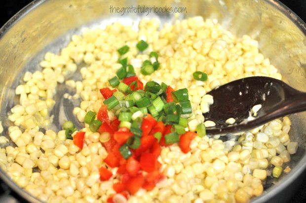Chopped red bell pepper and green onions are added to corn in skillet