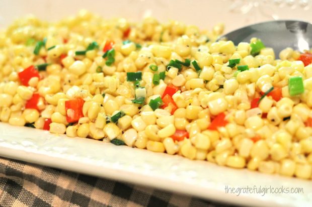 Fresh corn saute with red pepper and onions is served on white platter