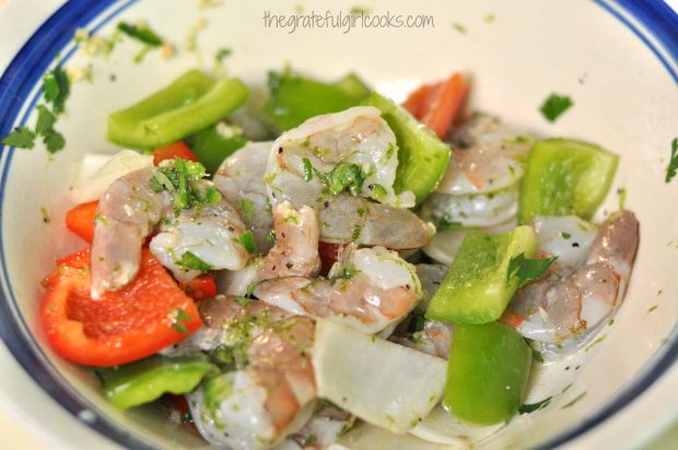 Red and green peppers and onions are mixed with the marinated shrimp.