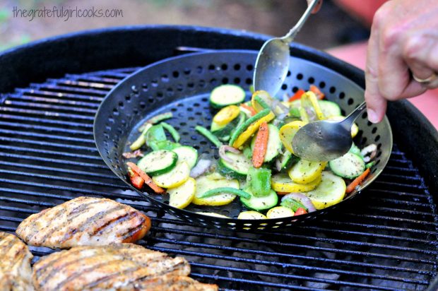 Grilled Summer Veggies on the BBQ, being stirred while they cook.