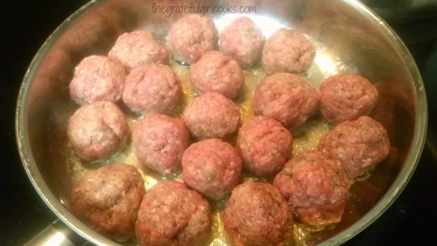 Meatballs browning in oil in large skillet