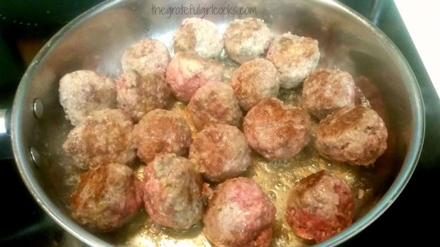 Browned meatballs for meatballs stroganoff are cooking in silver skillet.