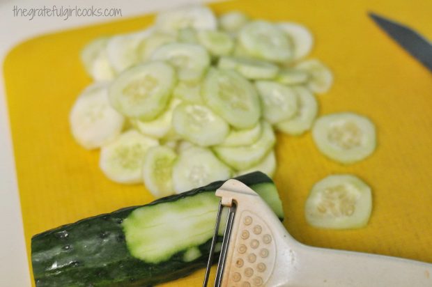 Cucumber is peeled and sliced (on yellow cutting mat)