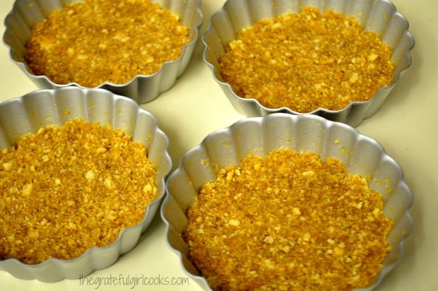 Graham cracker mixture is baked in mini tart pans.
