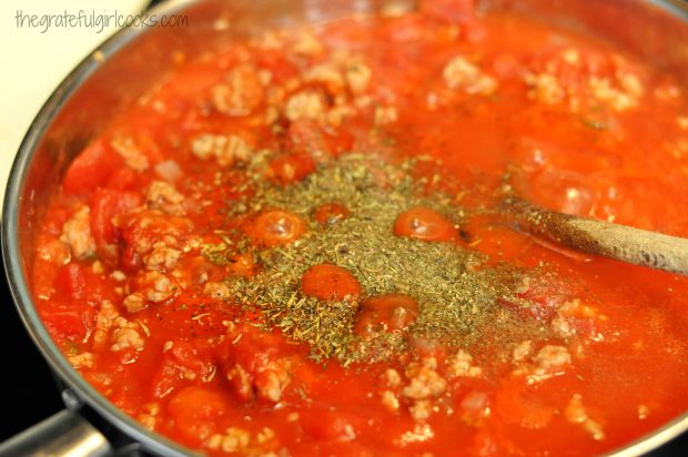 Dried Italian spices are added to skillet to season spaghetti sauce.