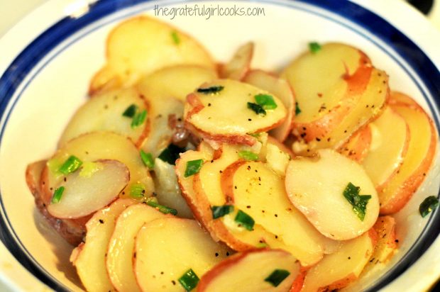 Skillet Potatoes are garnished with butter, seasoning and green onions.