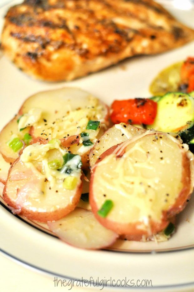 A close-up photo of the skillet potatoes, served with chicken (in background).