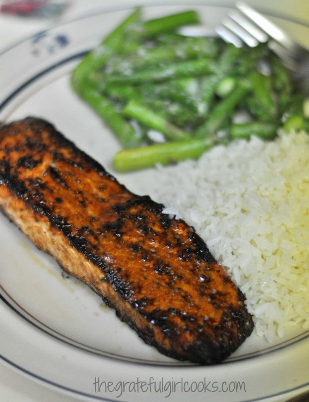 A brown sugar crusted salmon fillet is served with rice and steamed asparagus.