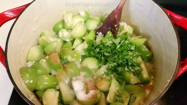 Cilantro, water, and spices added to sauce in pan