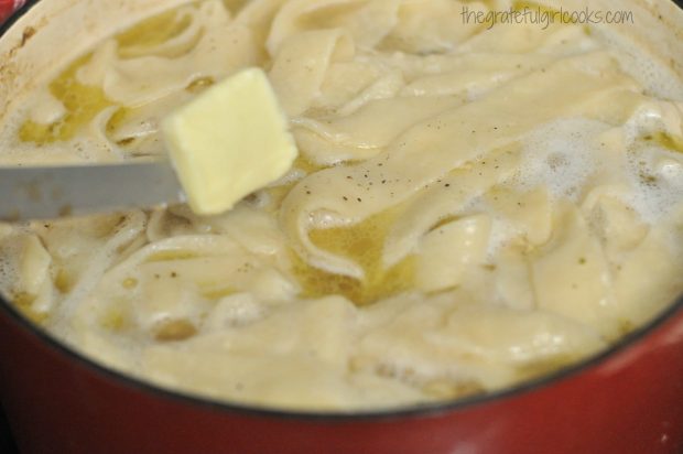 Butter, salt and pepper are added to chicken n' dumplings in pot