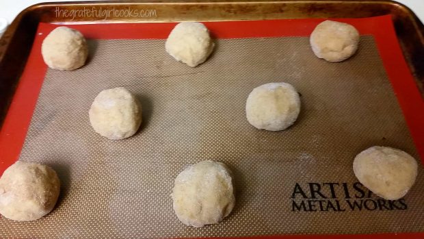 The sugar coated cookie balls are placed onto baking sheet.