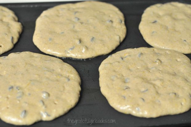 Pumpkin chocolate chip pancakes cooking on a griddle.