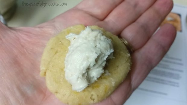 A spoonful of cheesecake filling is placed on flattened cookie dough.