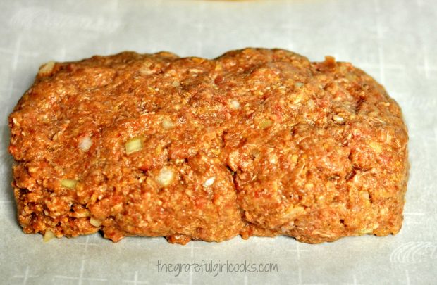 Meat is shaped into a loaf shape, on parchment paper lined baking sheet.