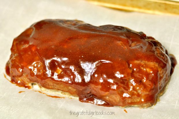 Half-baked meatloaf is covered with sauce, then put back into oven to finish cooking.