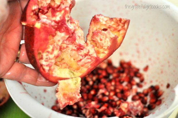 Pomegranate seeds fall out of skin into bowl,