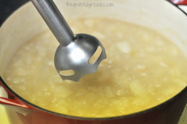 Immersion blender in pan of apples to blend