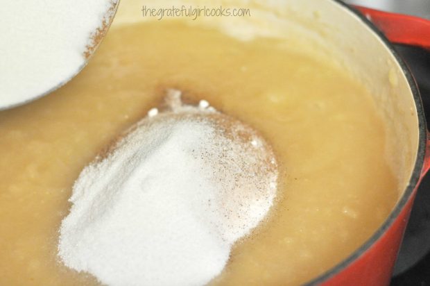 Adding sugar and spices to apple puree in pan