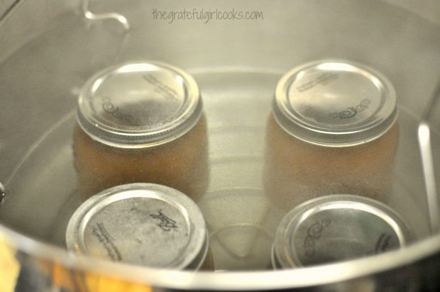 Jars of apple butter sitting in water in canner