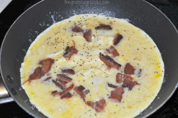 Cooked, crumbled bacon is added to eggs for breakfast burritos.