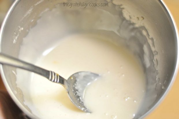 Orange glaze is ready to drizzle on top of cranberry orange muffins.