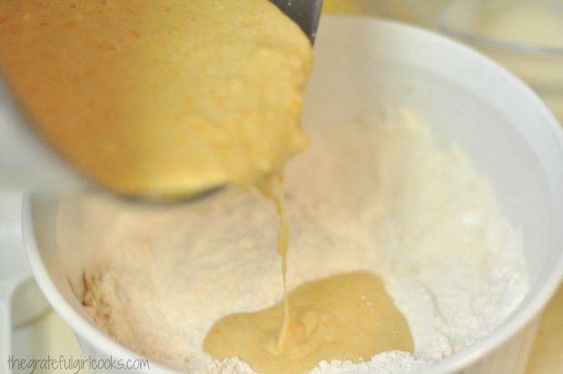 Wet muffin batter is added to dry ingredients for cranberry orange muffins.