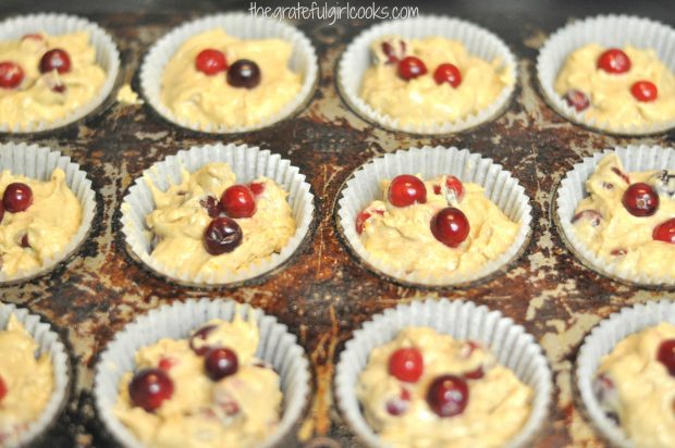 Cranberry orange muffins batter is placed into paper liners in pan before baking.