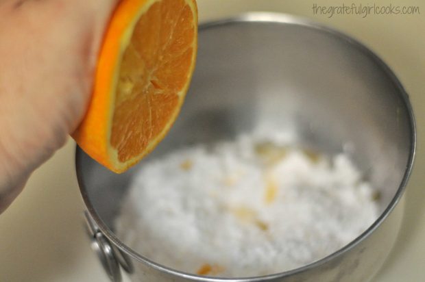 Squeezing orange juice into glaze mixture for icing cranberry orange muffins.