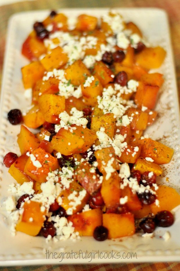 Honey, feta cheese, parsley and cinnamon are added to top of the roasted butternut squash on platter.