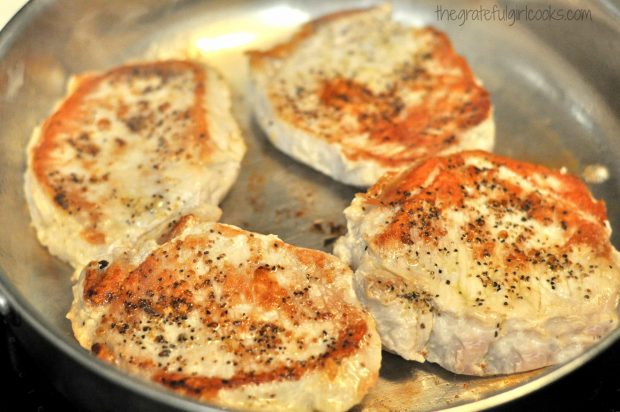 Seared pork chops in skillet.