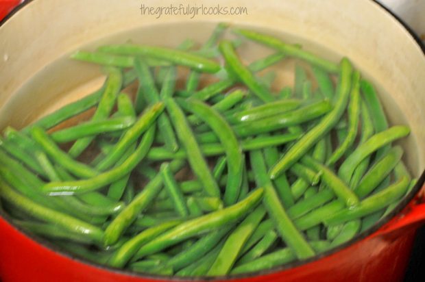 Green beans are cooked briefly in water, to begin making this side dish.
