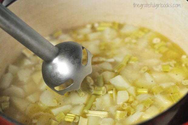 An immersion blender is used to puree the potatoes in the creamy potato leek soup.