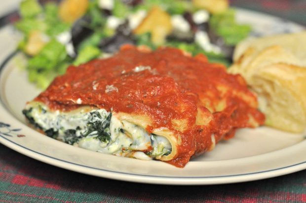 Florentine lasagna roll is served with salad and bread, on plate