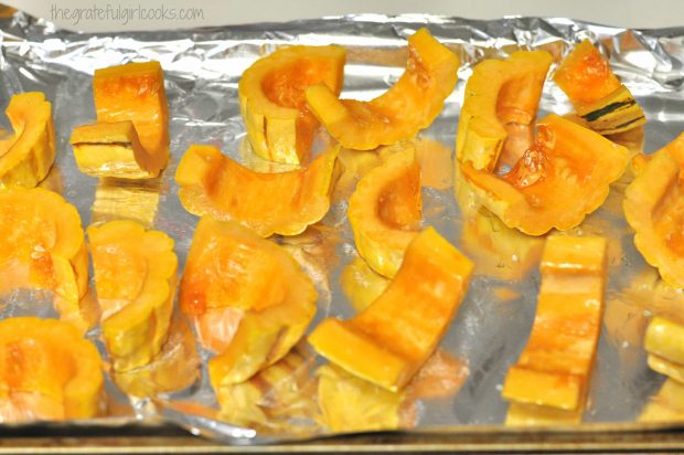 Roasted Delicata Squash slices are cooked on aluminum foil covered baking sheet in oven