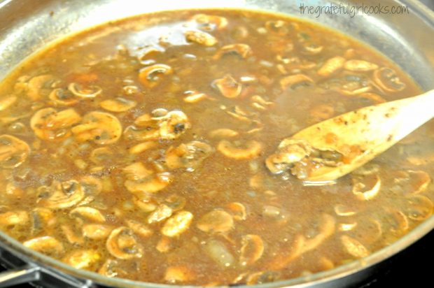 Mushrooms and onions cooking in beef broth in skillet