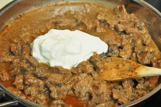 Sour cream added to beef and sauce in metal skillet