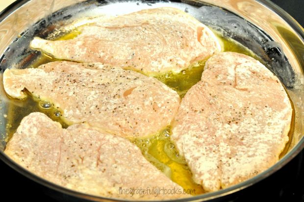 Cooking four floured chicken cutlets in hot oil in large skillet.