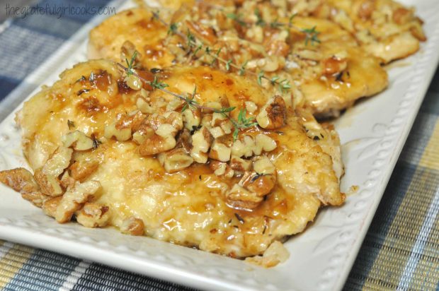 Chicken cutlets with pecan sauce are served on a white platter.