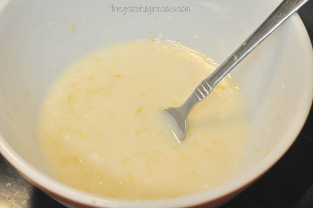 Lemon glaze for cake is mixed up in bowl.